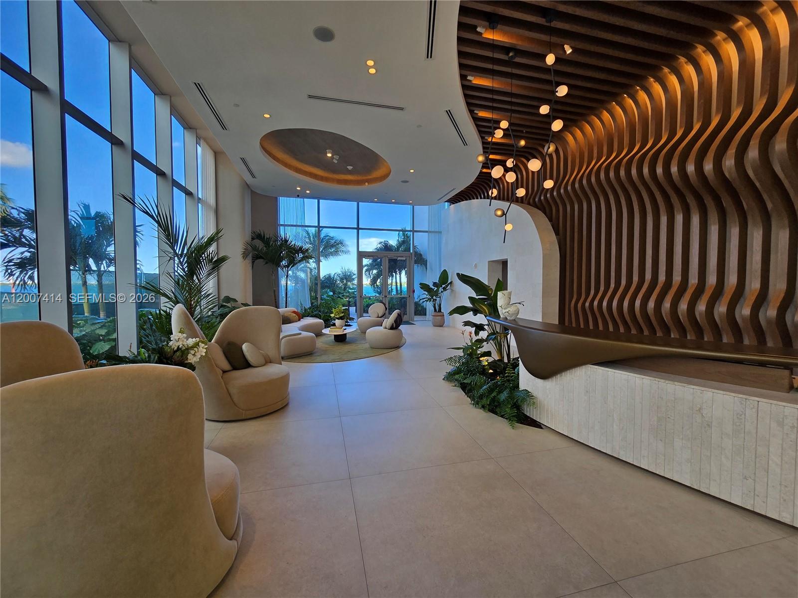 A modern lobby features a curved wood-slat wall, a reception desk, and floor-to-ceiling windows — 700 NE 24 ST # 3104, Miami FL 33137, MIAMI, FL
