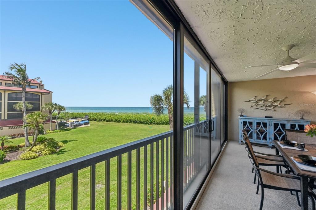 A covered balcony features a dining set, a blue sideboard, and views of the ocean — 8710 MIDNIGHT PASS ROAD UNIT 203B, SARASOTA, FL