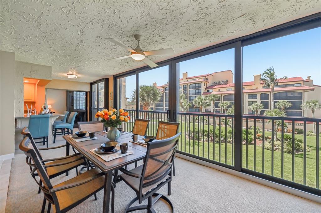 A dining area with a table and chairs sits on a balcony overlooking a courtyard — 8710 MIDNIGHT PASS ROAD UNIT 203B, SARASOTA, FL
