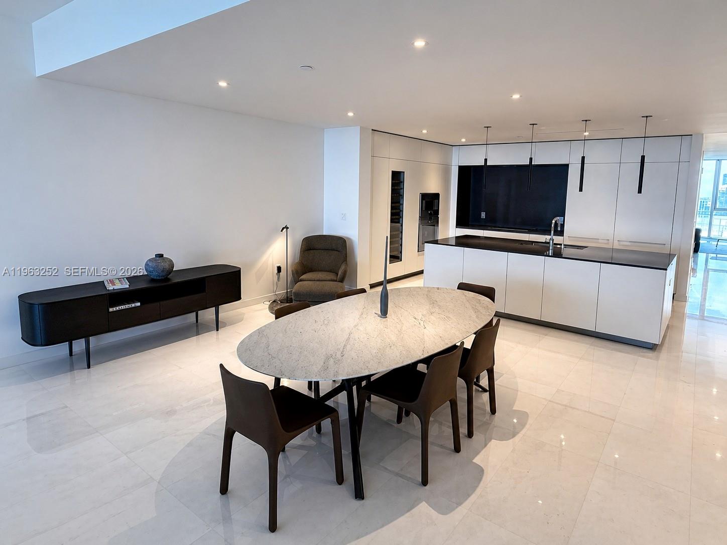 A modern open-plan kitchen and dining area features a marble oval table and white cabinetry — 300 Biscayne Blvd Way # 4404, Miami FL 33131, MIAMI, FL