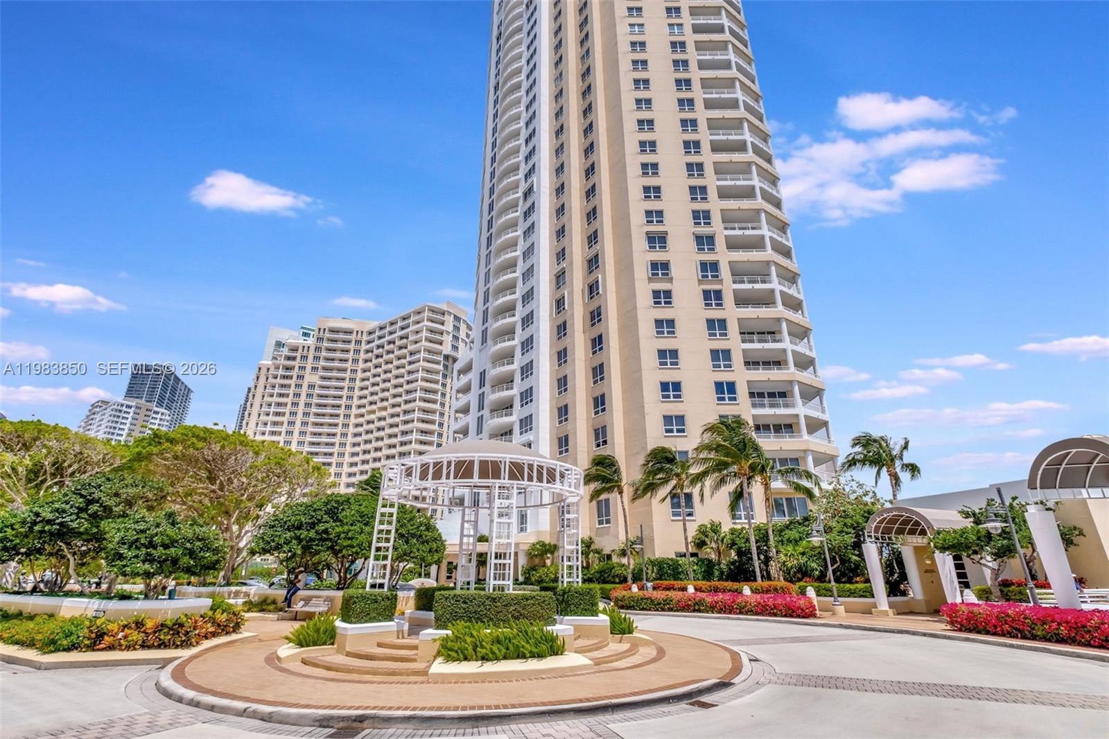A tall residential tower stands behind a landscaped roundabout with a white metal gazebo — 848 Brickell Key Dr # 2602, Miami FL 33131, MIAMI, FL