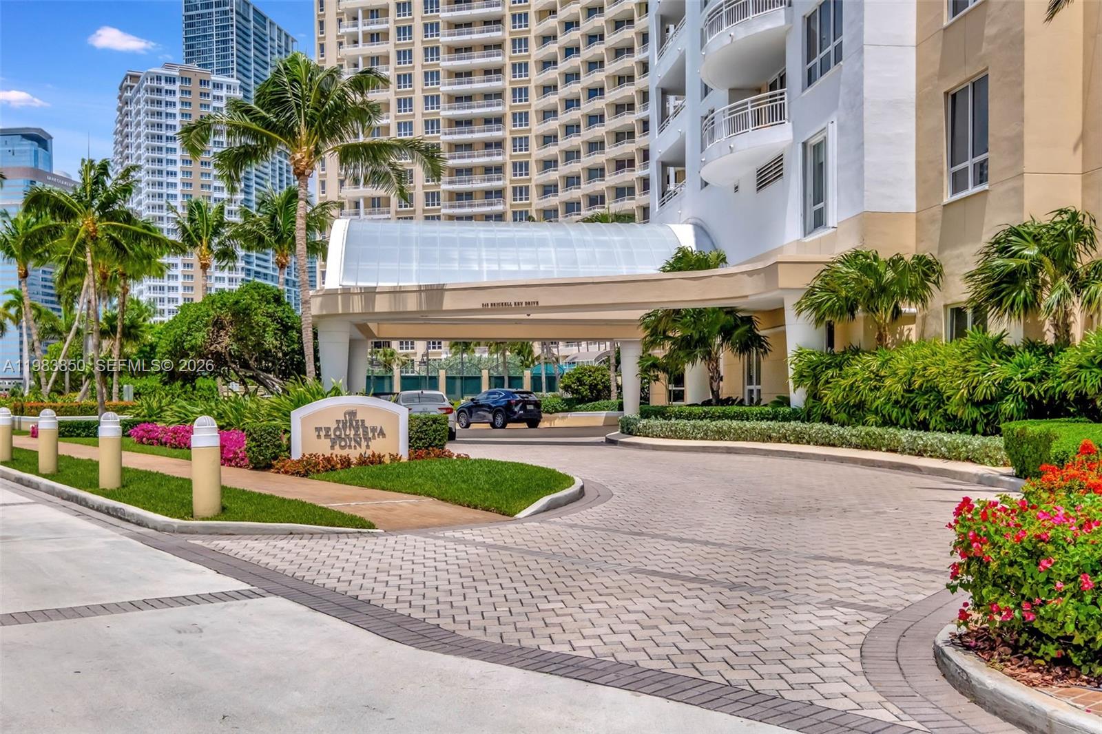The exterior entrance of a high-rise residential building features a covered driveway and landscaping — 848 Brickell Key Dr # 2602, Miami FL 33131, MIAMI, FL