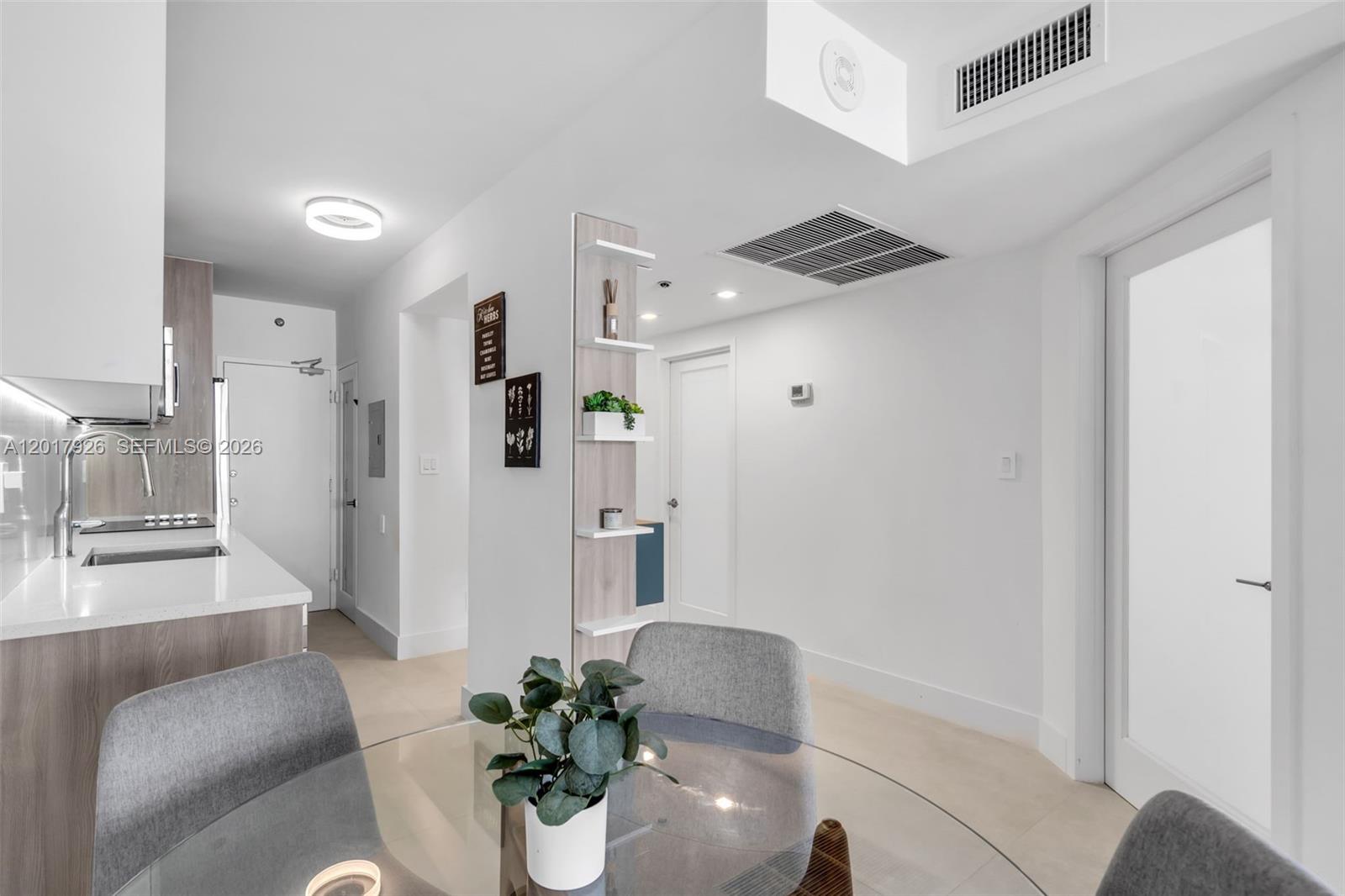 A modern kitchen and dining area feature white walls, light wood cabinetry, and gray chairs — 100 Lincoln Rd # 539, Miami Beach FL 33139, MIAMI BEACH, FL