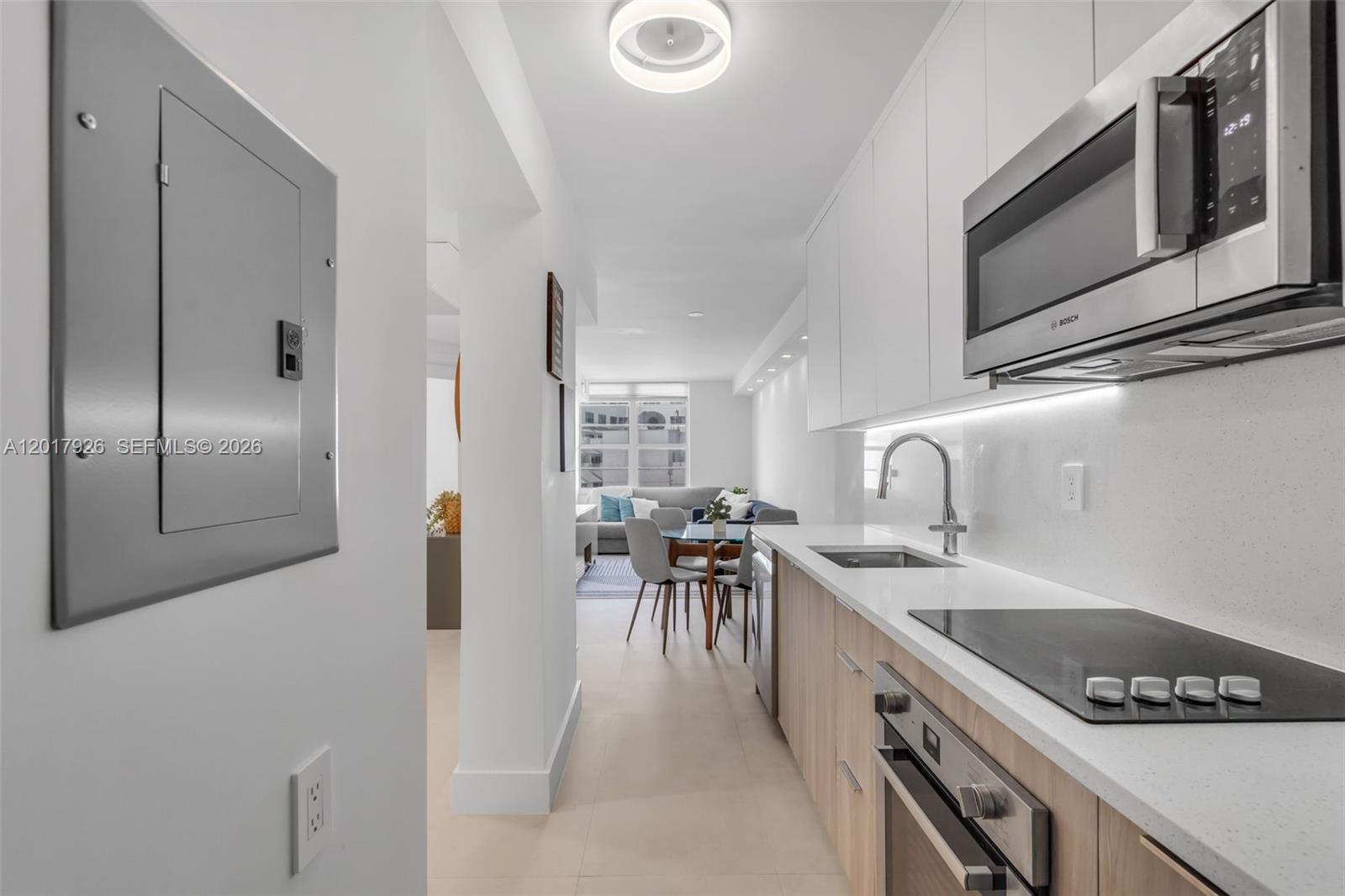 A modern galley kitchen features light wood cabinets, white countertops, and stainless steel appliances — 100 Lincoln Rd # 539, Miami Beach FL 33139, MIAMI BEACH, FL