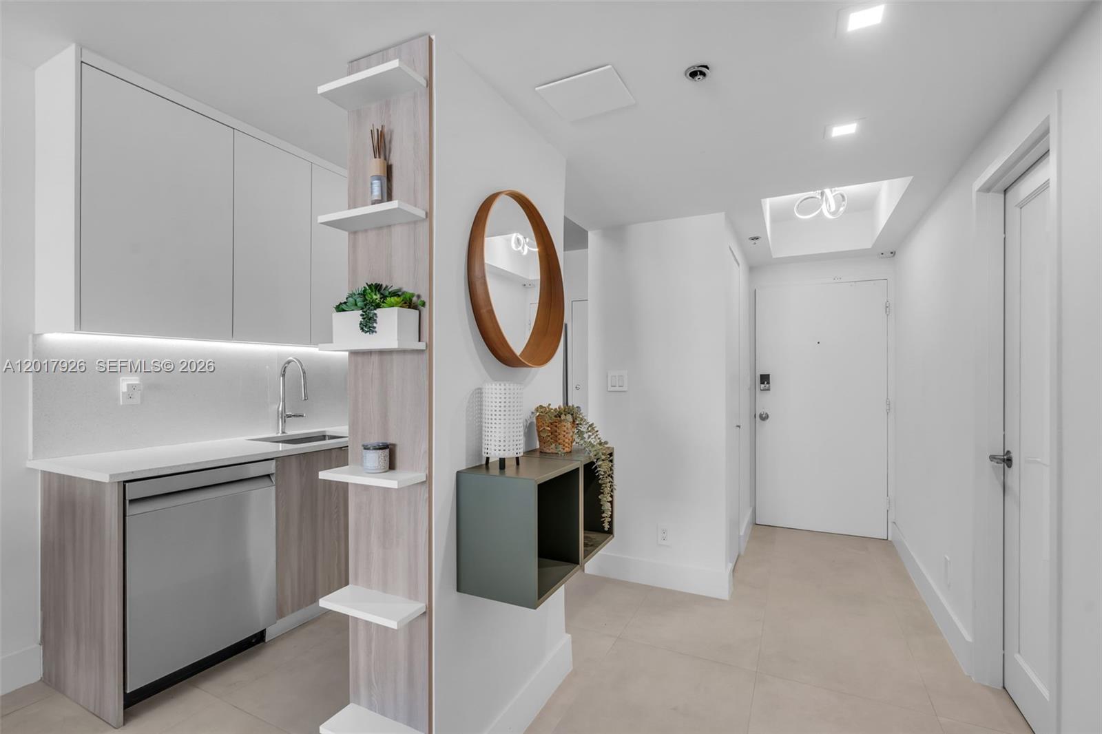 A modern kitchen area features white cabinetry, a wood-toned shelving unit, and a hallway entrance — 100 Lincoln Rd # 539, Miami Beach FL 33139, MIAMI BEACH, FL