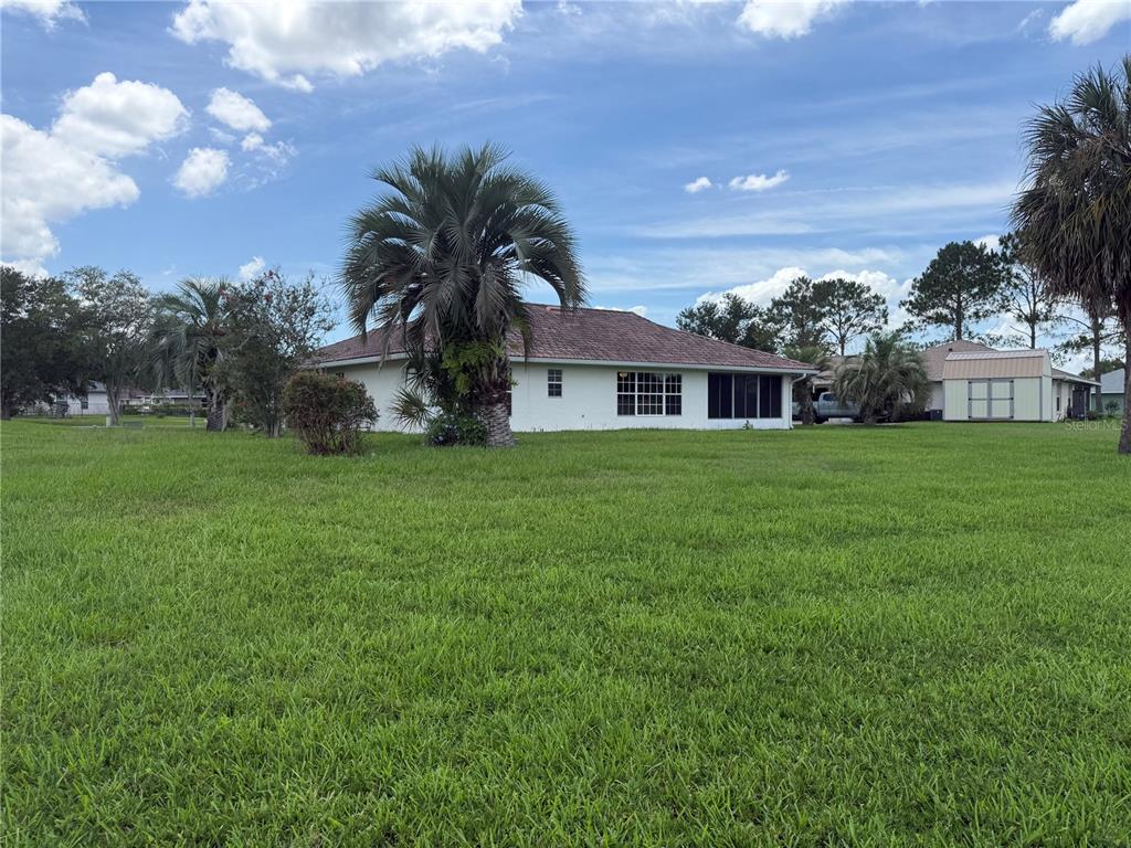 A white house with a tiled roof sits on a large, grassy lot with palm trees — 5 HICKORY LOOP, OCALA, FL