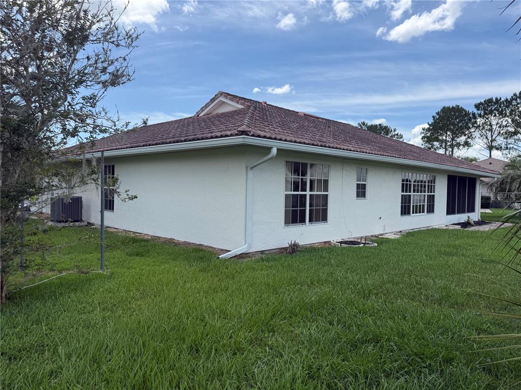 The exterior side of a single-story house with a tiled roof and white stucco walls — 5 HICKORY LOOP, OCALA, FL