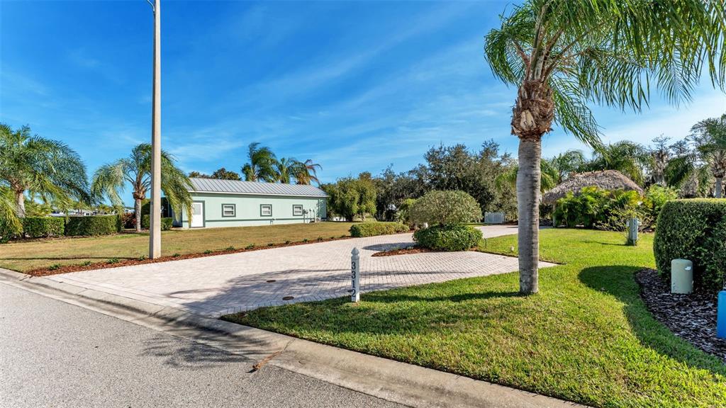 A paved driveway leads to a light green building with a metal roof and palm trees — 3312 FISH HAWK DRIVE, POLK CITY, FL