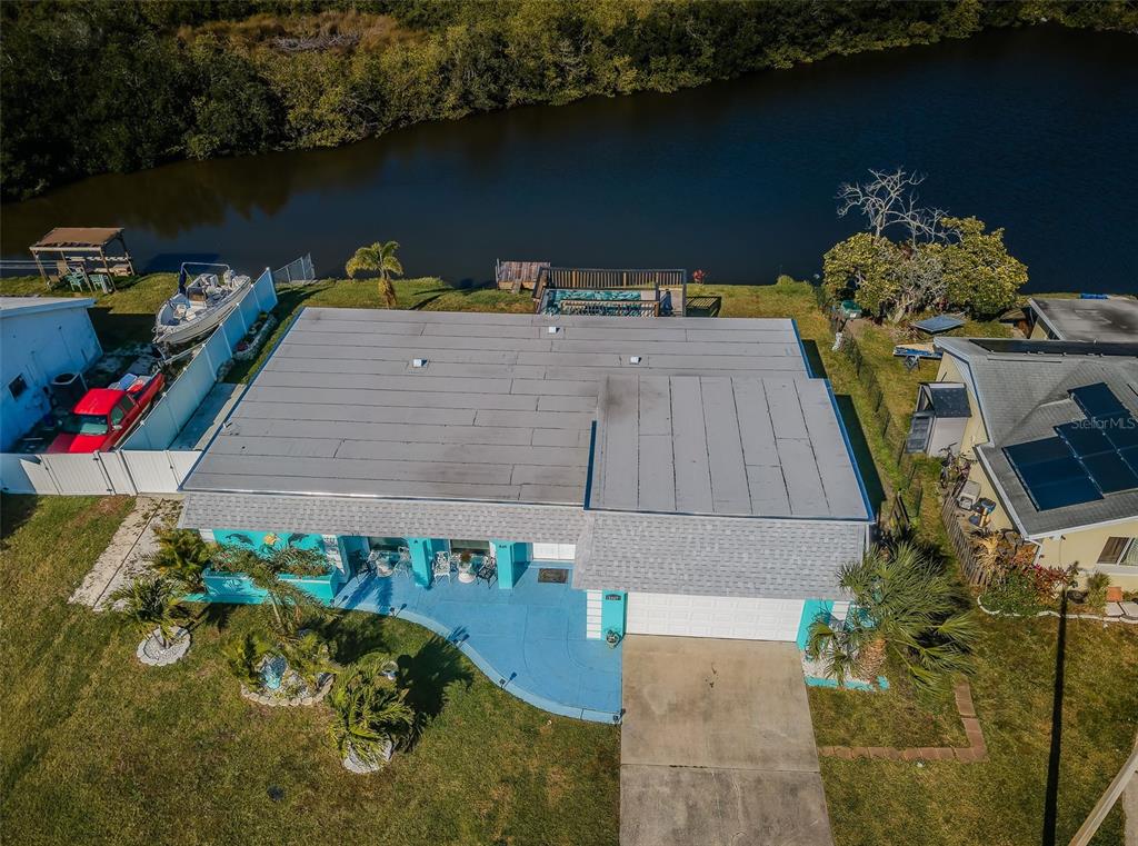 An aerial view shows a house with a flat roof, blue patio, and waterfront backyard — 3627 GRAYTON DRIVE, NEW PORT RICHEY, FL