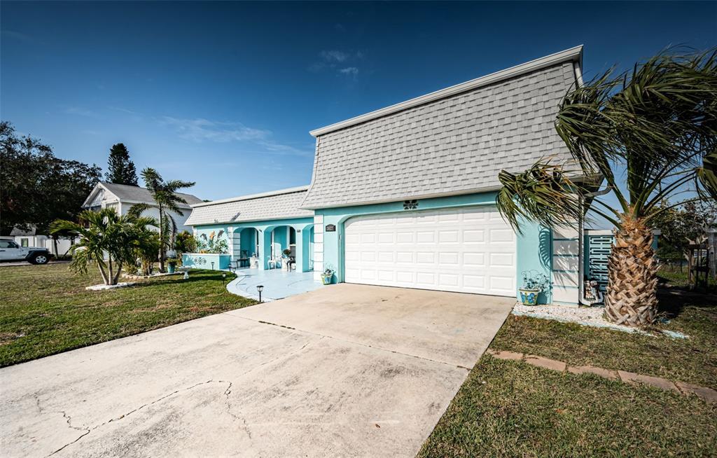A light blue single-story house with a large gray shingled roof and a white garage — 3627 GRAYTON DRIVE, NEW PORT RICHEY, FL