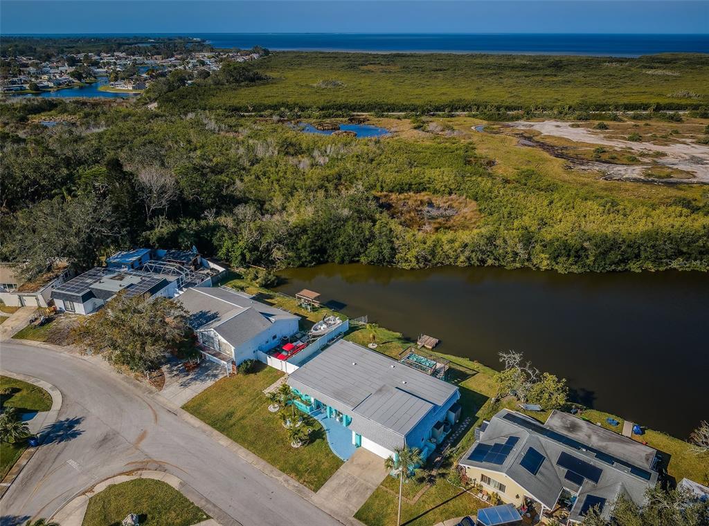 An aerial view shows waterfront houses with solar panels along a curved residential street — 3627 GRAYTON DRIVE, NEW PORT RICHEY, FL