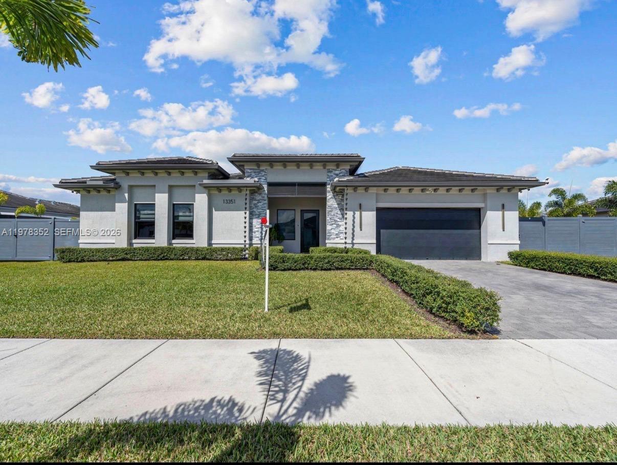 A single-story house with a gray stucco exterior, stone accents, and a two-car garage — 13351 SW 190th St, Miami FL 33177, MIAMI, FL