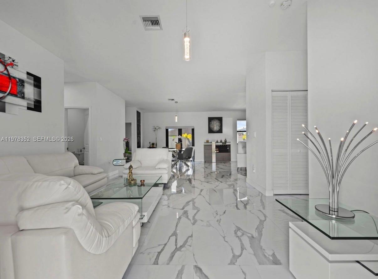 A bright living room features white leather furniture, marble-patterned tile floors, and modern decor — 13351 SW 190th St, Miami FL 33177, MIAMI, FL