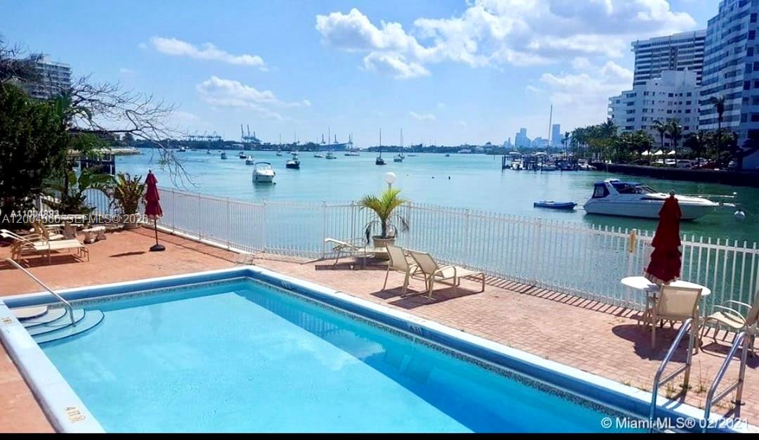 A swimming pool overlooks a bay with boats and city buildings in the distance — 1441 Lincoln Rd # 212, Miami Beach FL 33139, MIAMI BEACH, FL