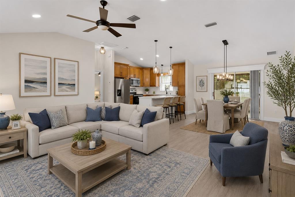 An open-concept living and dining area features a sectional sofa, kitchen island, and hardwood floors — 1213 EL ESPARZA LANE, THE VILLAGES, FL