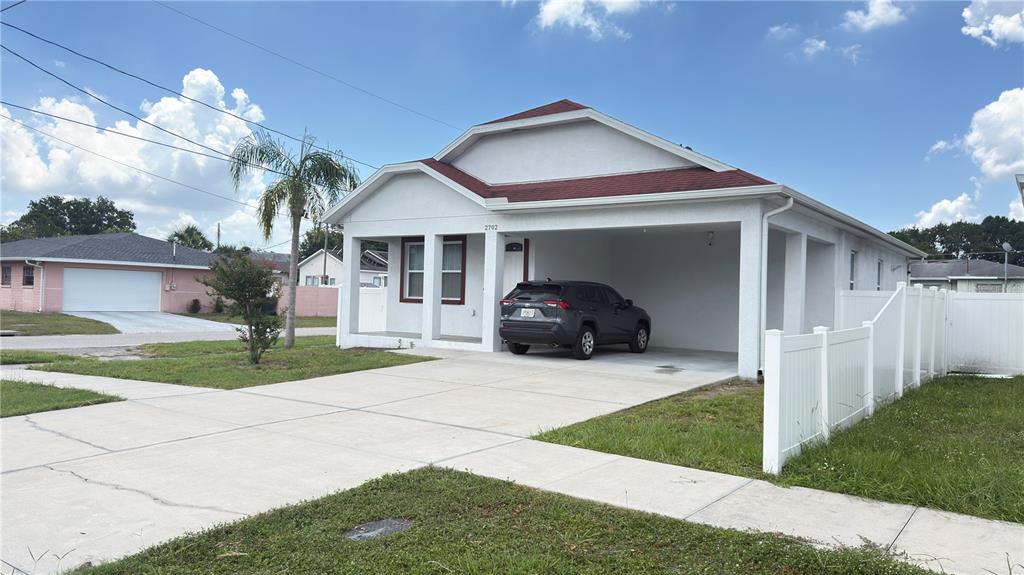 A white single-story house with a red roof and an attached carport — 2702 W SAINT CONRAD STREET, TAMPA, FL