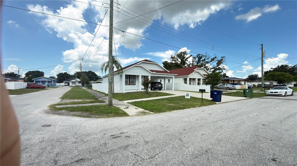 A white single-story house with a carport and a front yard sits on a corner — 2702 W SAINT CONRAD STREET, TAMPA, FL
