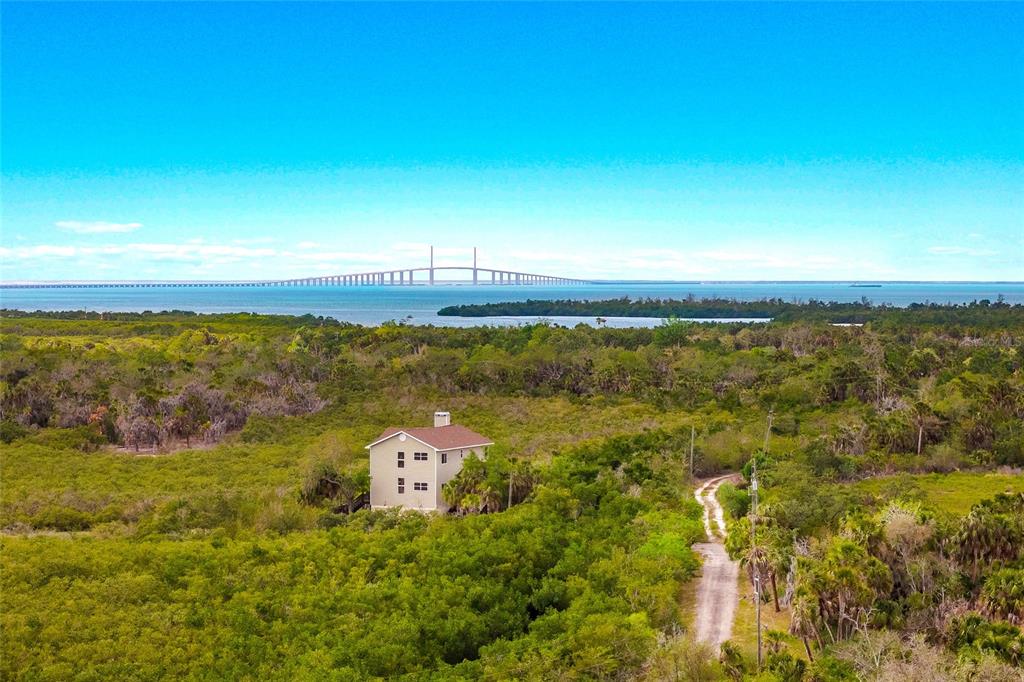A three-story house features stacked screened porches, a rooftop deck, and a tall chimney — 7325 HOLLY ROAD, TERRA CEIA, FL