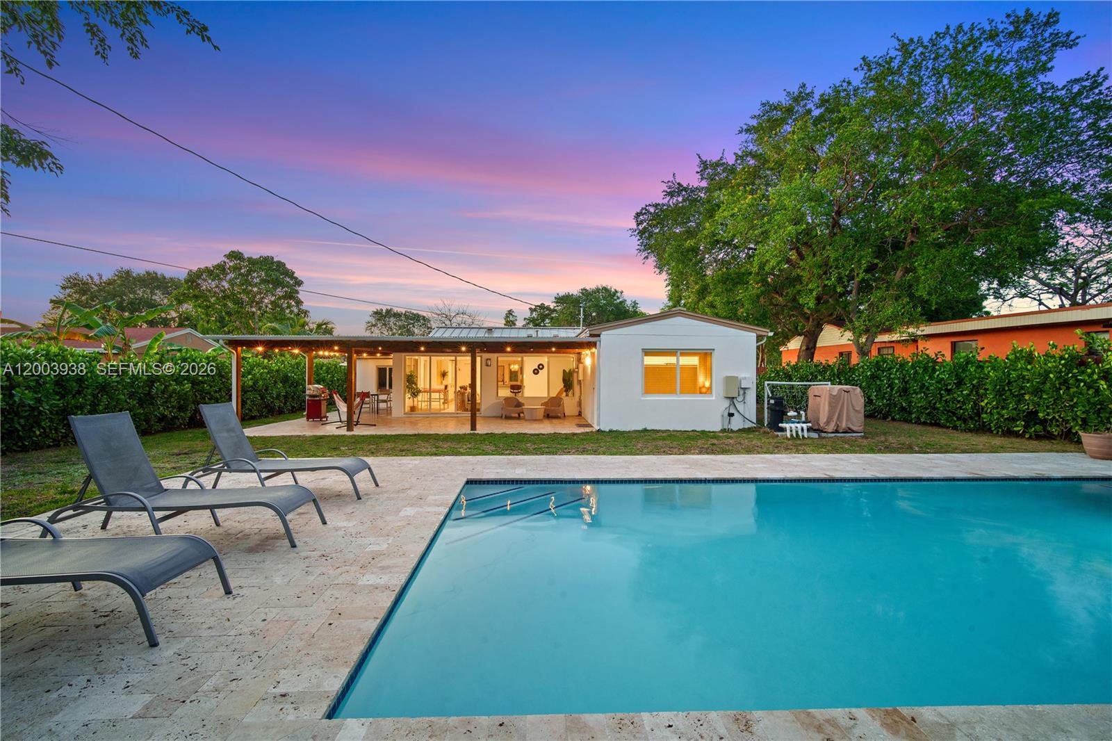 A backyard features a swimming pool, lounge chairs, and a covered patio attached to a house — 1360 NE 138th St, North Miami FL 33161, NORTH MIAMI, FL
