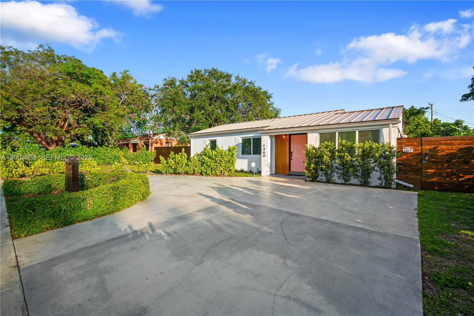 A single-story house with a metal roof, pink front door, and a concrete driveway — 1360 NE 138th St, North Miami FL 33161, NORTH MIAMI, FL