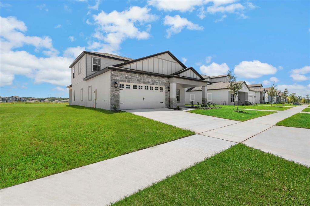 A two-story suburban house features a stone facade, a two-car garage, and a concrete driveway — 3368 CHINOTTO DRIVE, LAKE ALFRED, FL