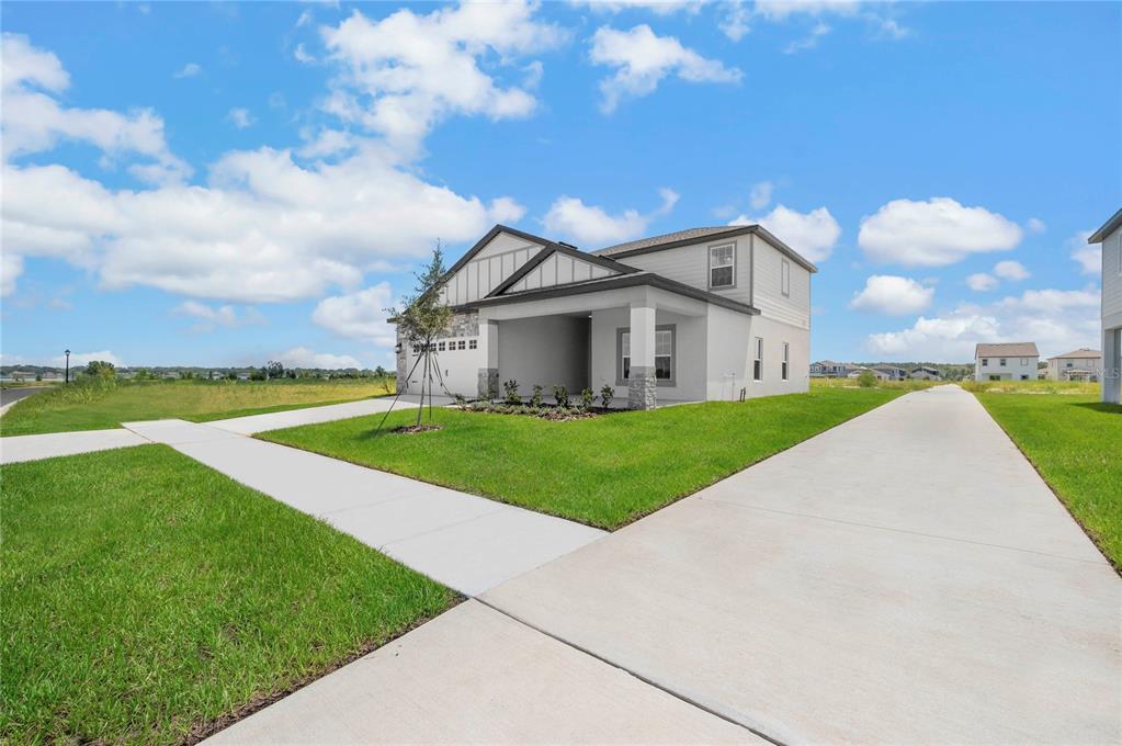 A two-story suburban house with a gray exterior, a front porch, and a concrete driveway — 3368 CHINOTTO DRIVE, LAKE ALFRED, FL