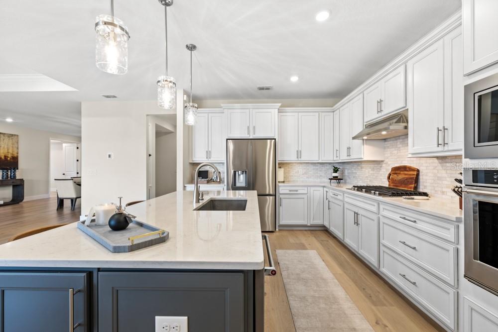 A modern kitchen features white cabinets, a dark gray island, and stainless steel appliances — 5148 FOOTHILLS PRESERVE LOOP, MOUNT DORA, FL