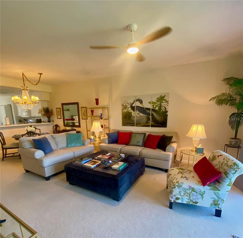 A living room features two beige sofas, a large navy ottoman, and a patterned armchair — 9590 HIGH GATE DRIVE UNIT 1915, SARASOTA, FL