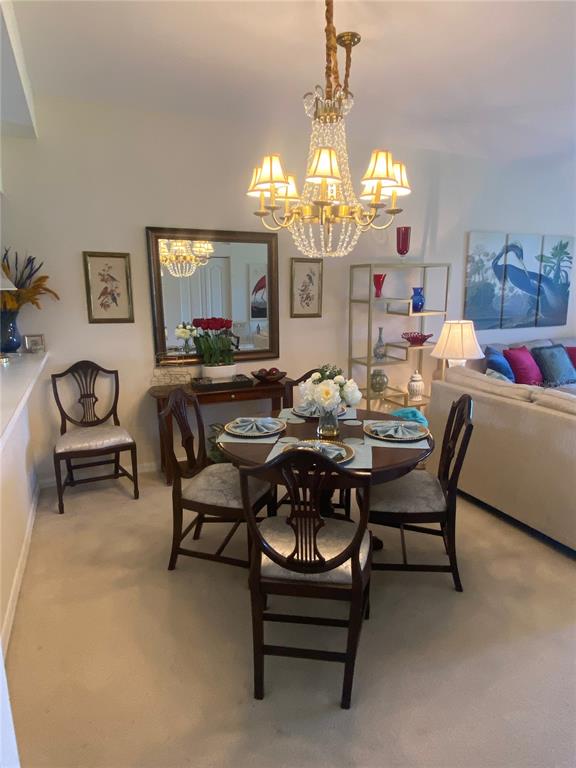 A dining area features a round table, four wooden chairs, and a crystal chandelier — 9590 HIGH GATE DRIVE UNIT 1915, SARASOTA, FL