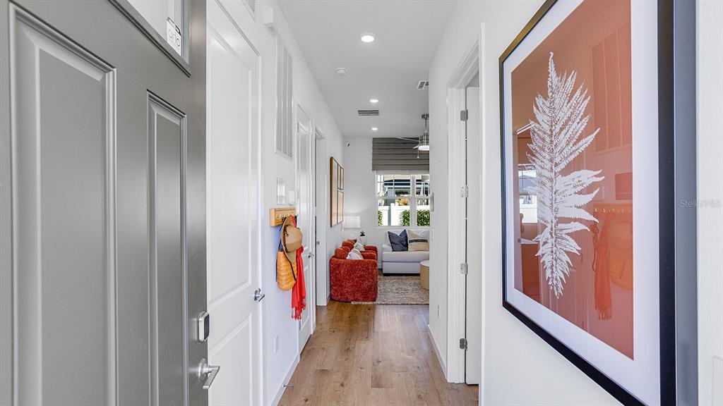 A hallway with wood flooring leads to a living area featuring a red sofa — 2507 KOJI STREET UNIT Elevate, MOUNT DORA, FL