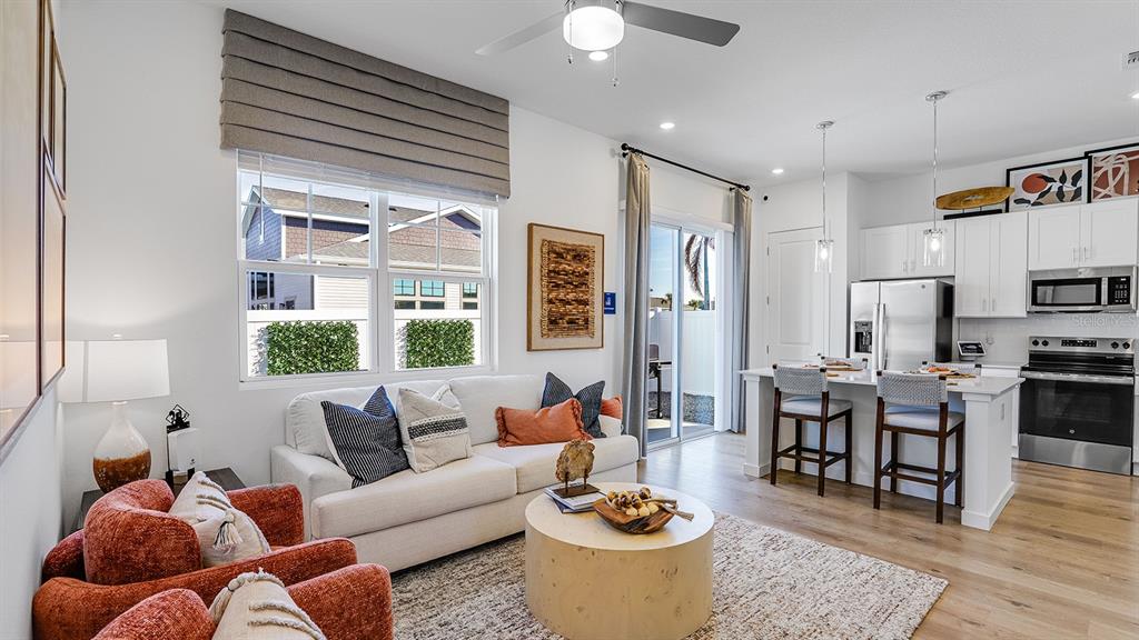 A living room and kitchen open-concept space features white cabinetry, a sofa, and armchairs — 2507 KOJI STREET UNIT Elevate, MOUNT DORA, FL