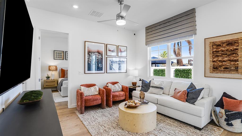 A living room features a white sofa, two orange armchairs, and a round wooden table — 2507 KOJI STREET UNIT Elevate, MOUNT DORA, FL
