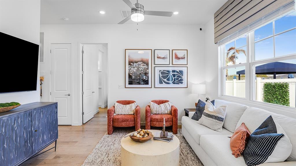 A living room features a white sofa, two orange armchairs, a blue cabinet, and artwork — 2507 KOJI STREET UNIT Elevate, MOUNT DORA, FL