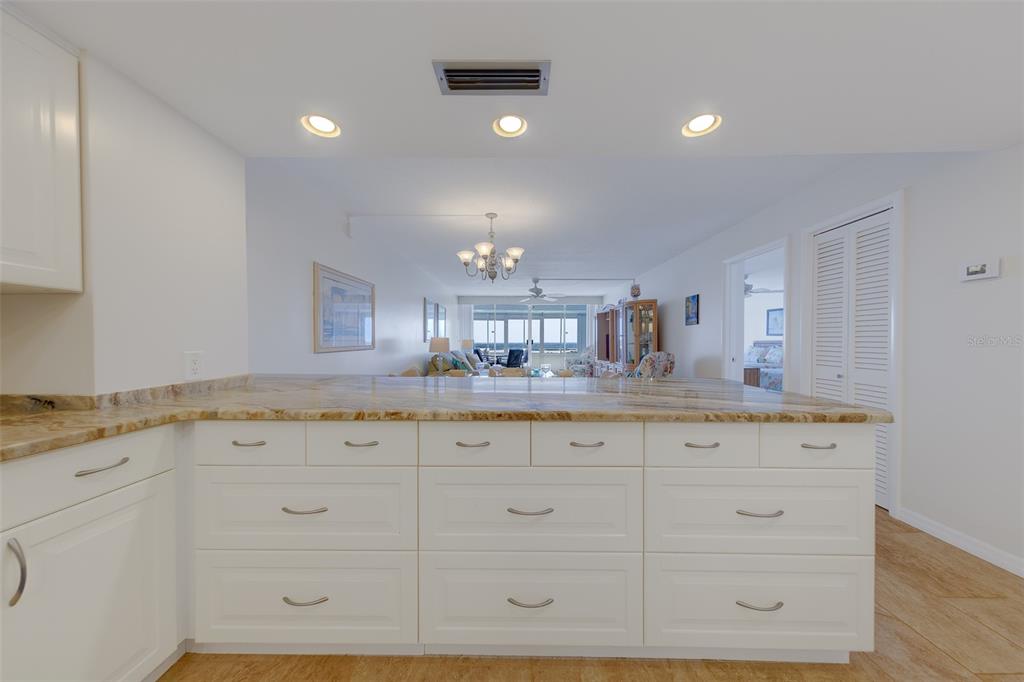 A white kitchen island with granite countertops faces an open-concept living area with ocean views — 17920 GULF BOULEVARD UNIT 1808, REDINGTON SHORES, FL