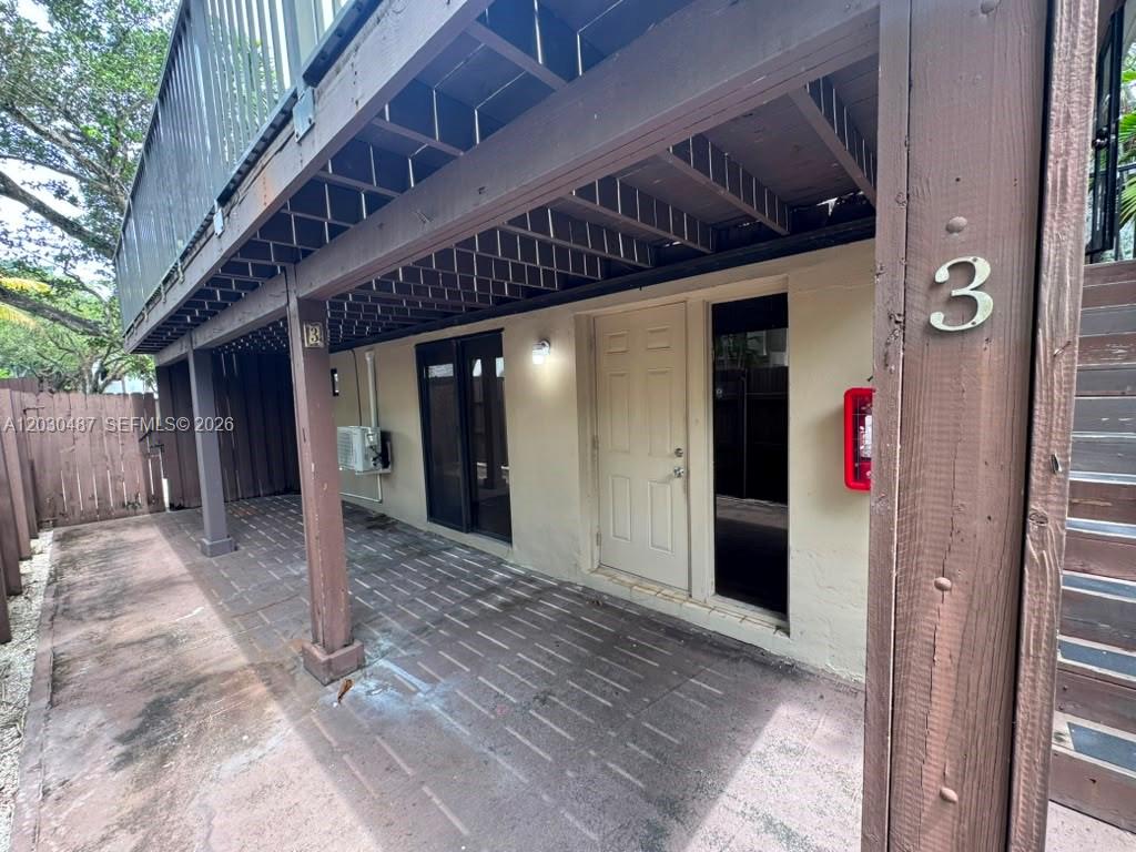 A ground-level patio area sits beneath a wooden deck with a numbered entrance door — 2107 Secoffee St # 3, Miami FL 33133, MIAMI, FL