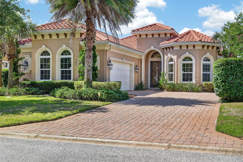 A single-story house with a tiled roof, arched windows, and a brick paver driveway — 167 ASPEN WAY, PALM COAST, FL