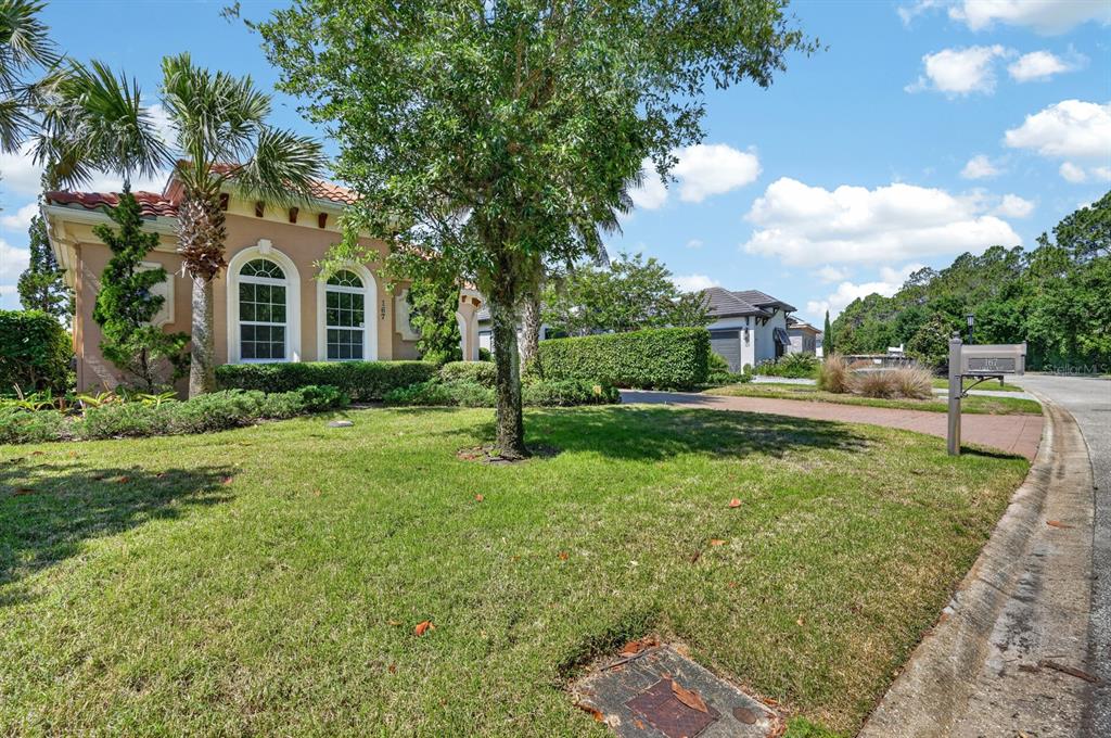A tan stucco house with arched windows and a tile roof sits behind a grassy lawn — 167 ASPEN WAY, PALM COAST, FL