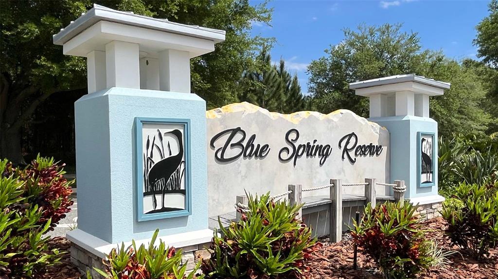 The entrance sign for Blue Spring Reserve features two light blue pillars and landscaping — 216 GLASS ONION DRIVE, HOWEY IN THE HILLS, FL