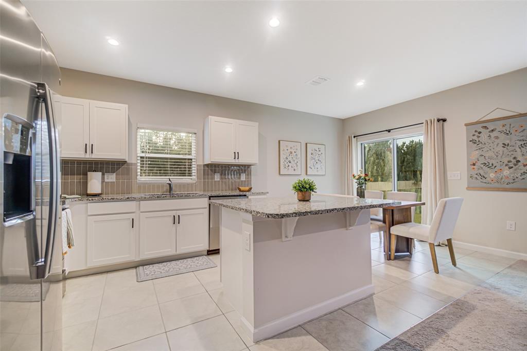 A kitchen with white cabinets, granite countertops, a center island, and a dining area — 1104 CATSKILL DRIVE, HAINES CITY, FL