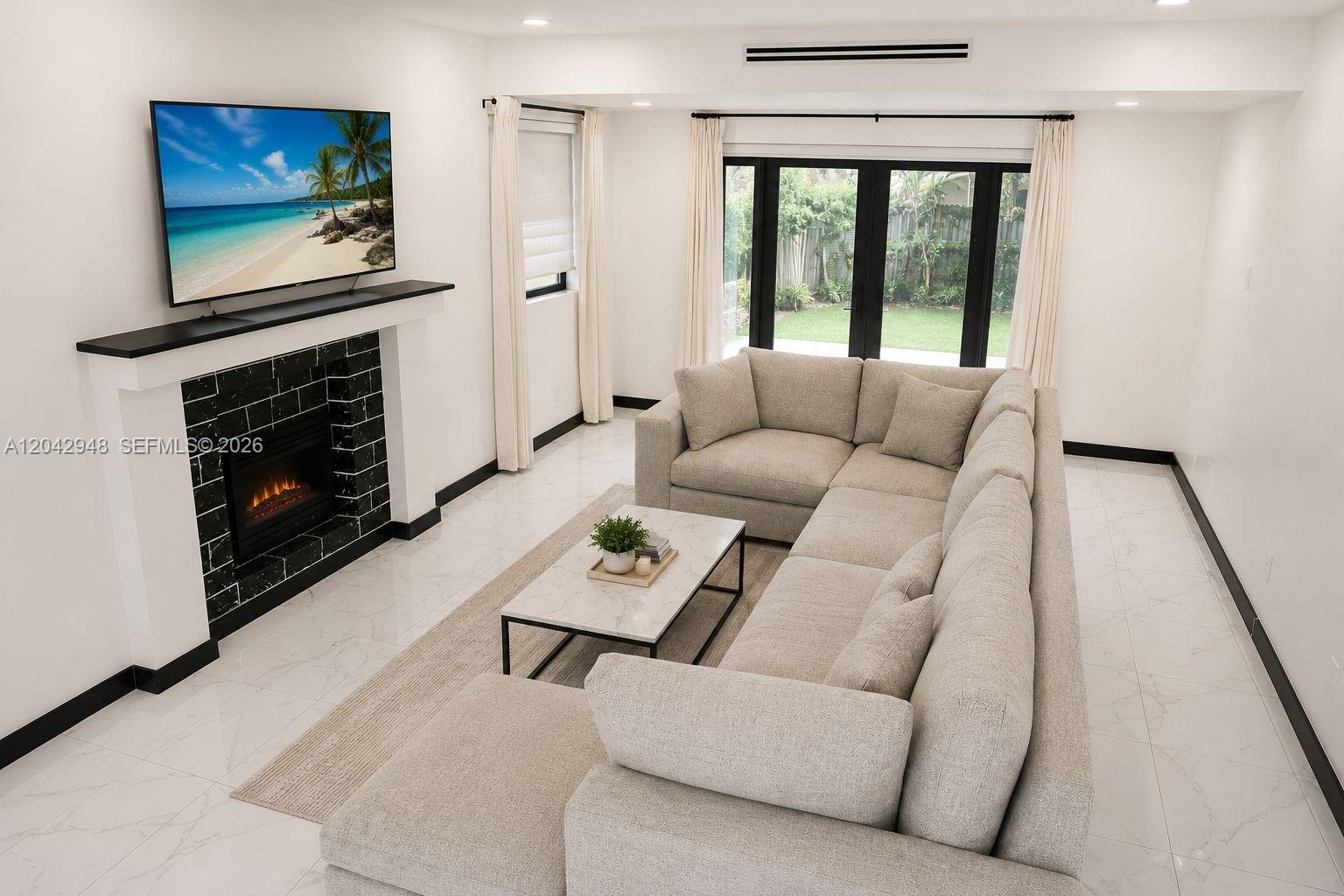 A modern living room features a black-tiled fireplace, a large sectional sofa, and glass doors — 17790 SW 110th Ct, Miami FL 33157, MIAMI, FL