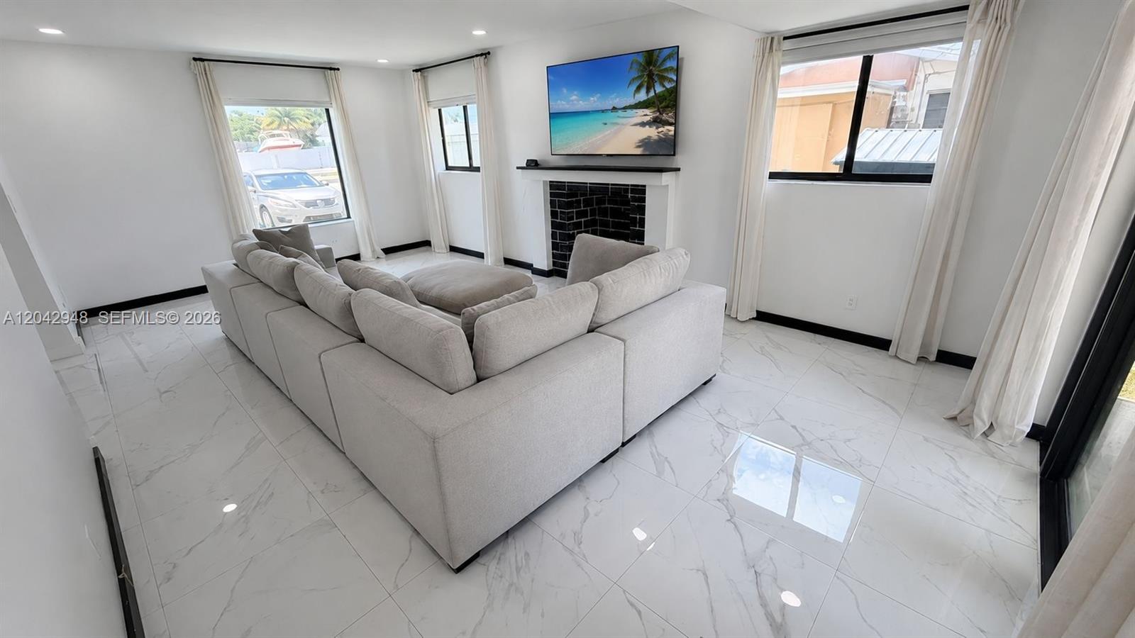 A living room features a large sectional sofa, a fireplace with a television, and tile flooring — 17790 SW 110th Ct, Miami FL 33157, MIAMI, FL