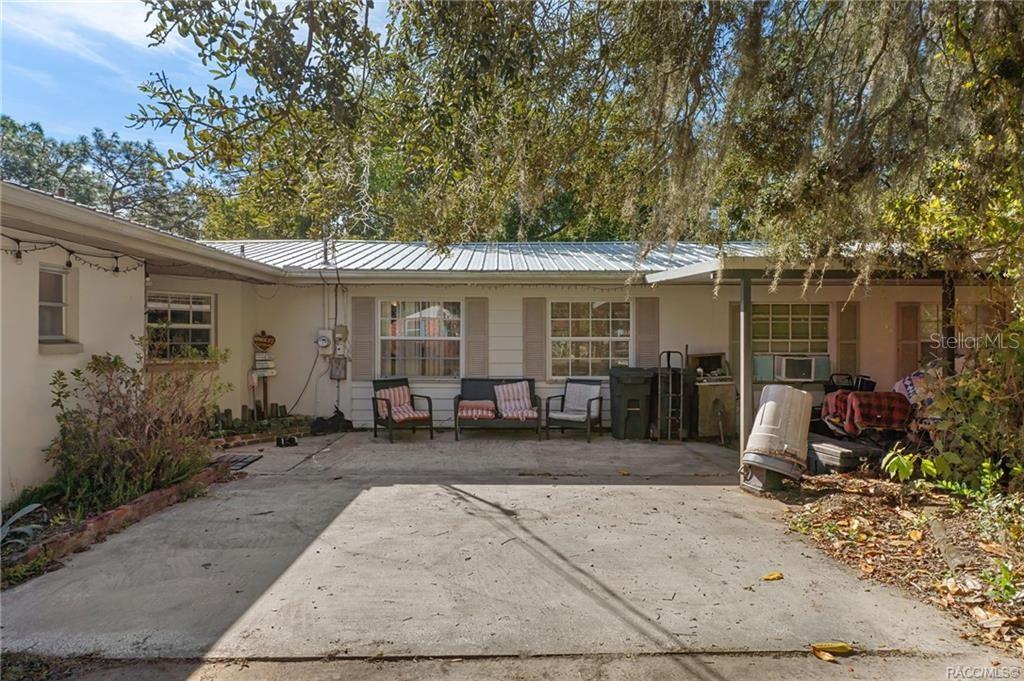A concrete patio sits in front of a white house with a metal roof — 8372 E LAKE BRADLEY ROAD, FLORAL CITY, FL