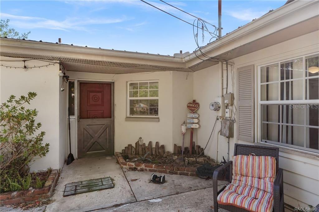 An exterior view of a home entrance with a red door and a small patio — 8372 E LAKE BRADLEY ROAD, FLORAL CITY, FL