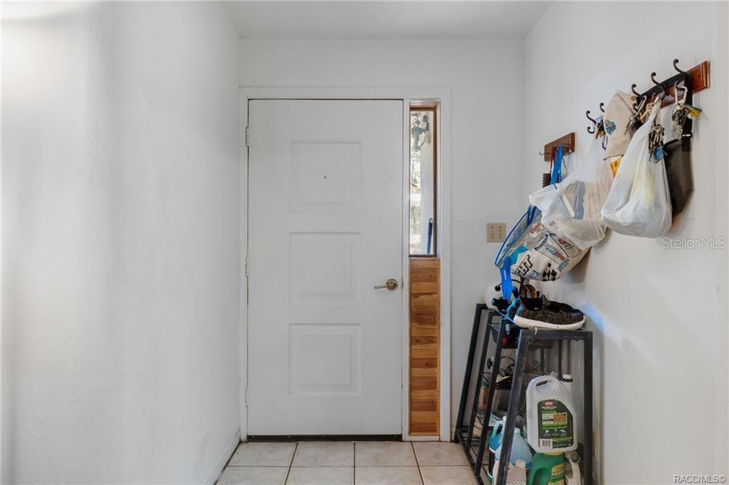 An entryway features a white door with a side window, tile flooring, and wall-mounted hooks — 8372 E LAKE BRADLEY ROAD, FLORAL CITY, FL