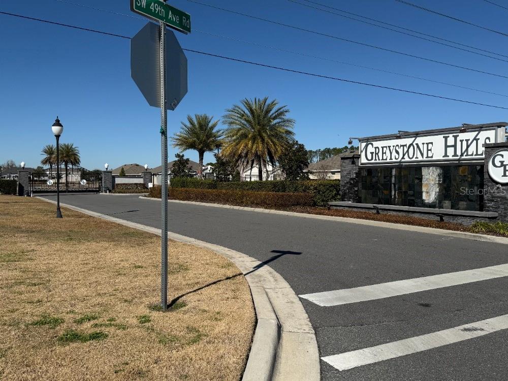 A gated residential community entrance features a stone monument sign and palm trees — 8953 SW 50TH TERRACE, OCALA, FL