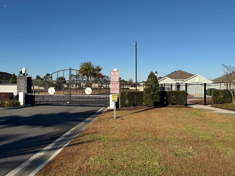 A gated entrance with a paved driveway leads to a residential community with landscaped grounds — 8953 SW 50TH TERRACE, OCALA, FL