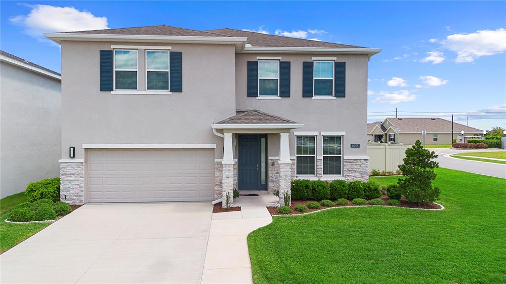 A two-story suburban house with a beige stucco exterior, stone accents, and a two-car garage — 8953 SW 50TH TERRACE, OCALA, FL