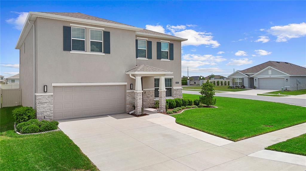 A two-story suburban house with a beige stucco exterior, stone accents, and a concrete driveway — 8953 SW 50TH TERRACE, OCALA, FL