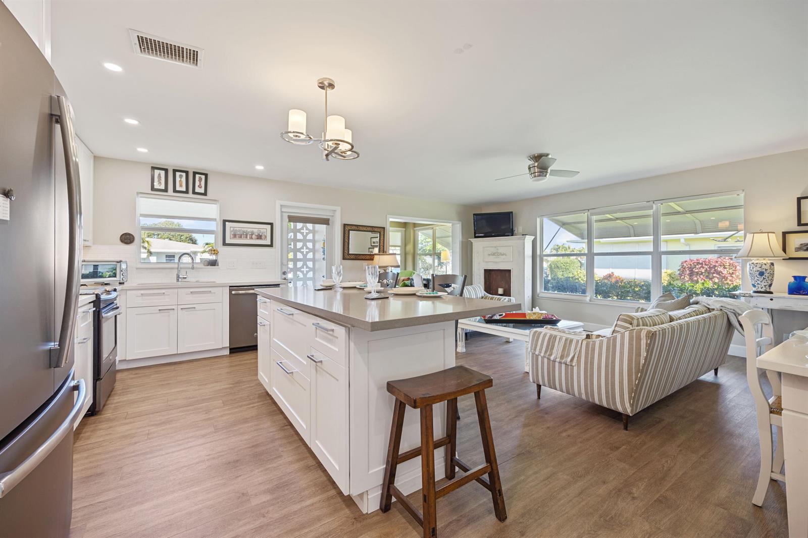 A kitchen with white cabinets and a center island opens into a living room area — 200 South Boulevard # A, Boynton Beach FL 33435, BOYNTON BEACH, FL
