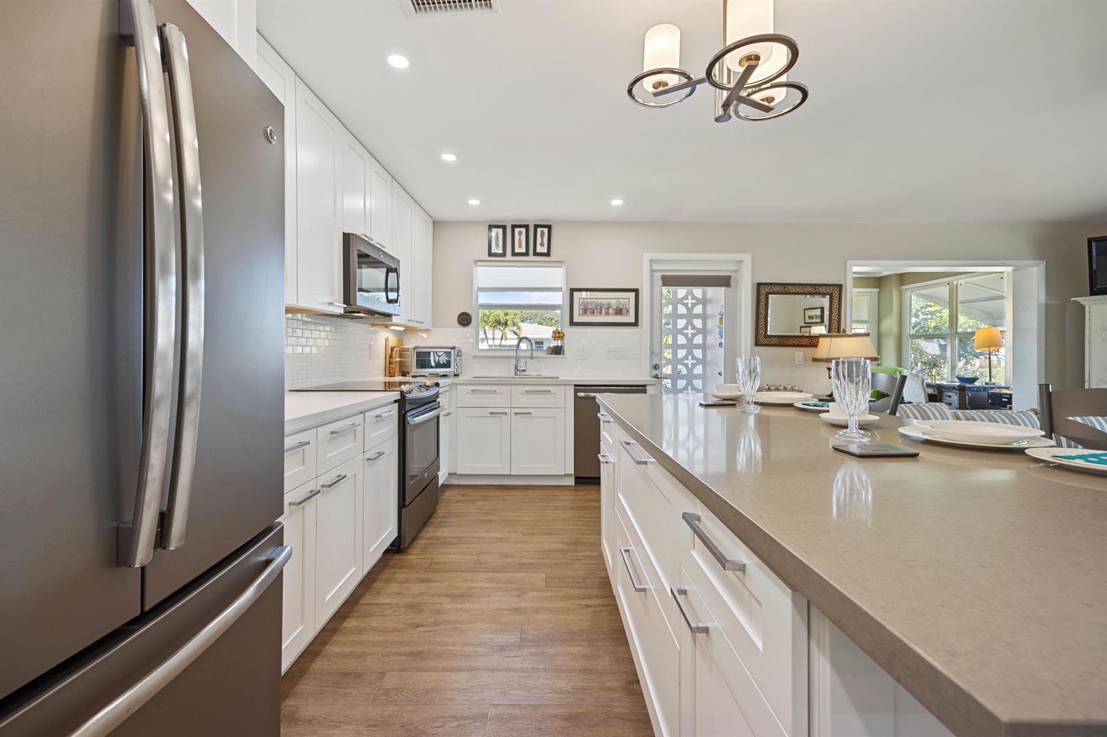 A modern kitchen features white cabinetry, stainless steel appliances, and a large central island — 200 South Boulevard # A, Boynton Beach FL 33435, BOYNTON BEACH, FL